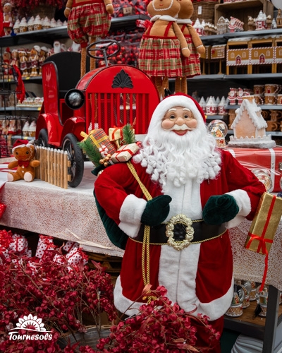 Père Noël au marché de Noël avec décorations festives et jouets.